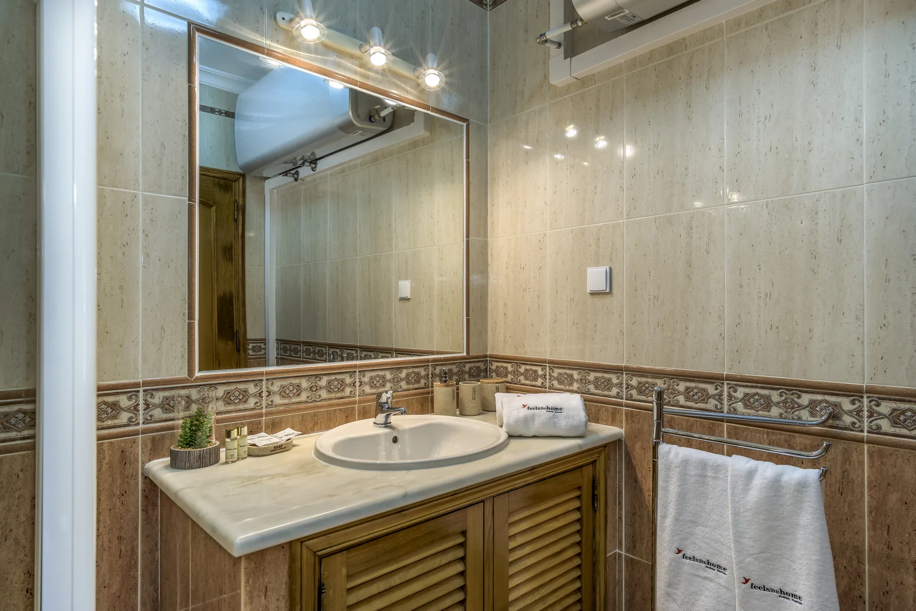 Un baño de azulejos con un lavabo bajo un espejo grande.