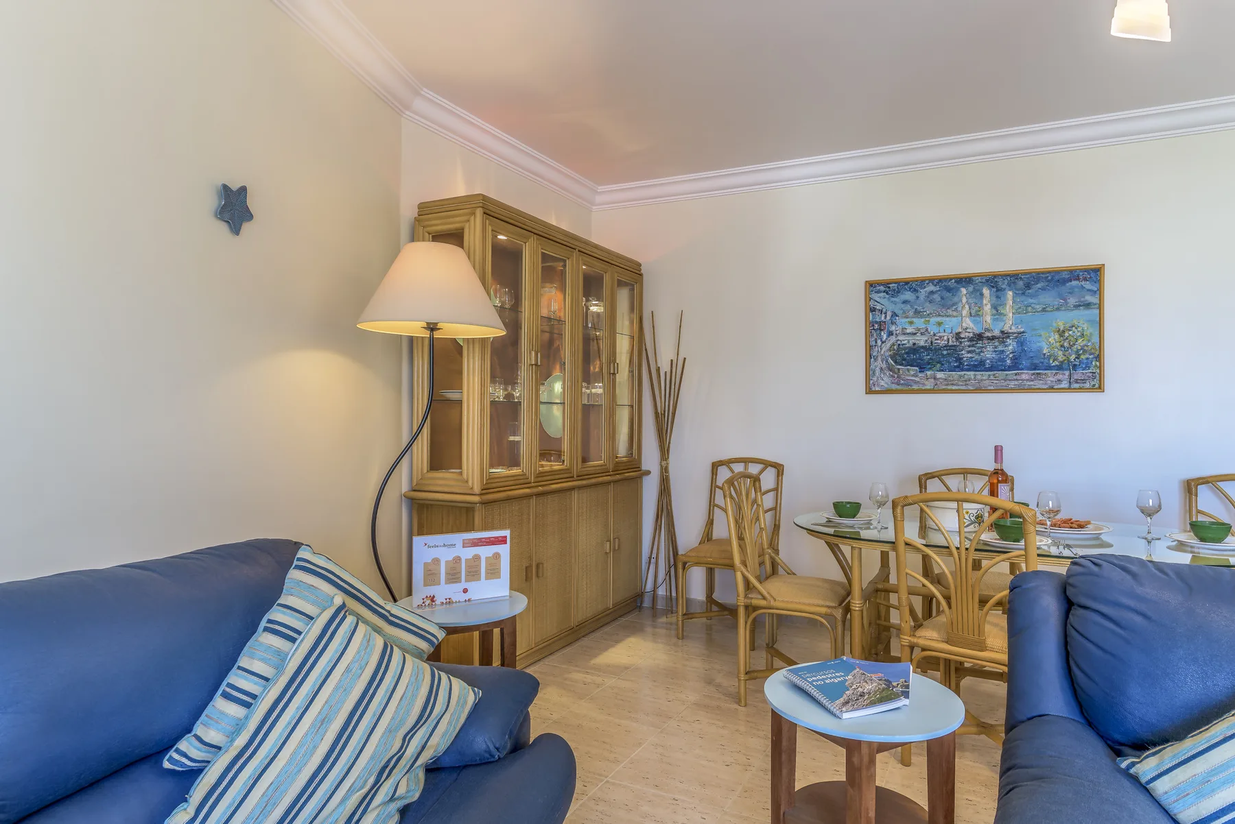 Un salón-comedor con asientos azules y un mueble expositor de madera.