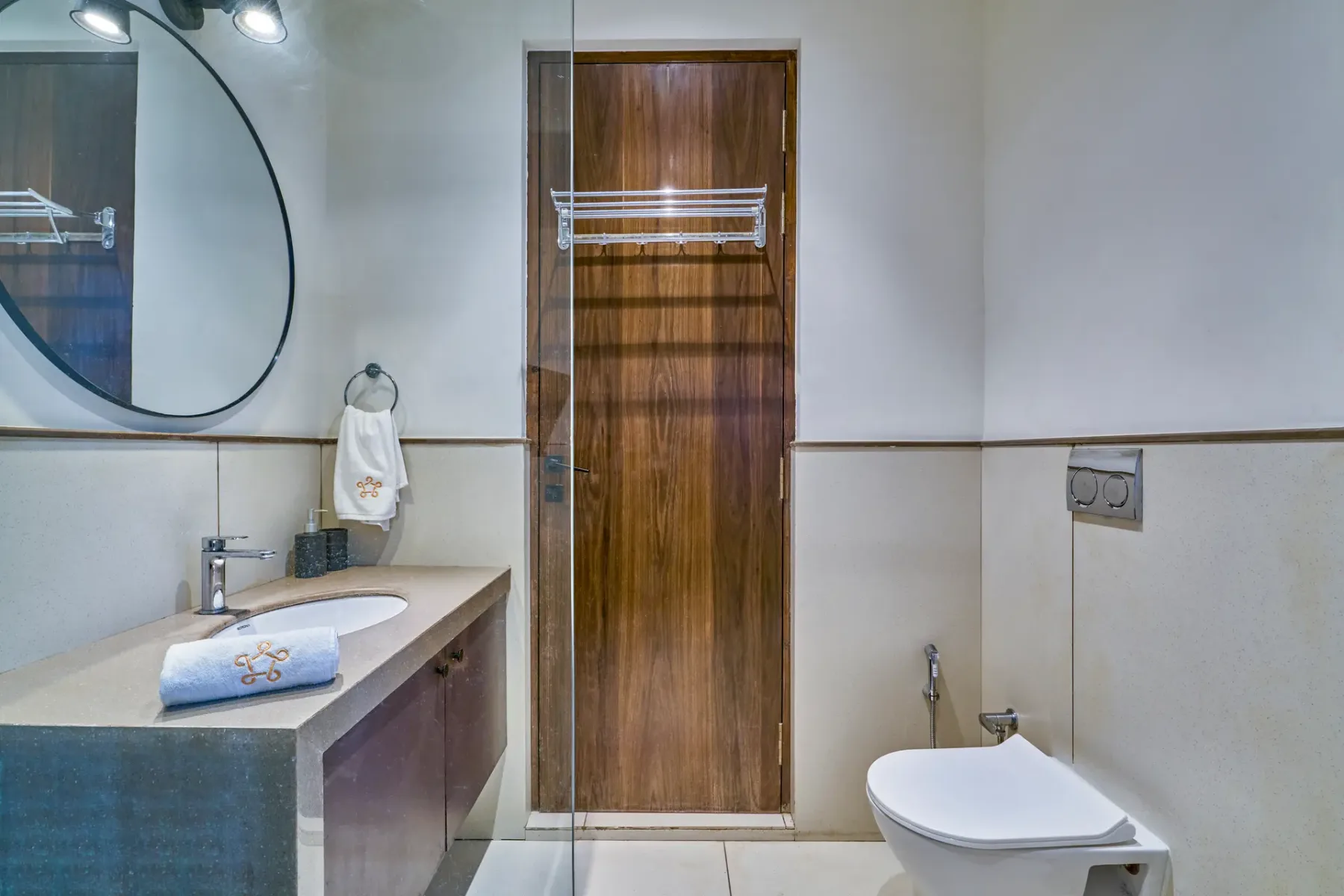 A bathroom with a sink, mirror, and toilet beside a wooden door.