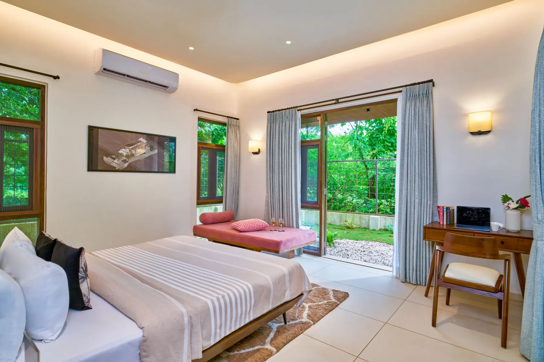 A bedroom with a bed beside open glass doors overlooking greenery.