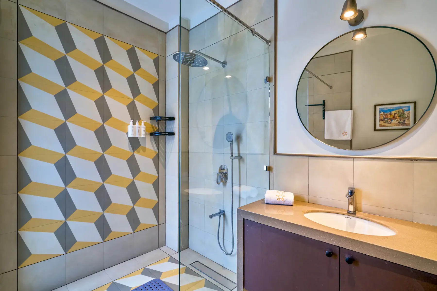A bathroom with a glass shower, patterned wall tiles, and a sink vanity.