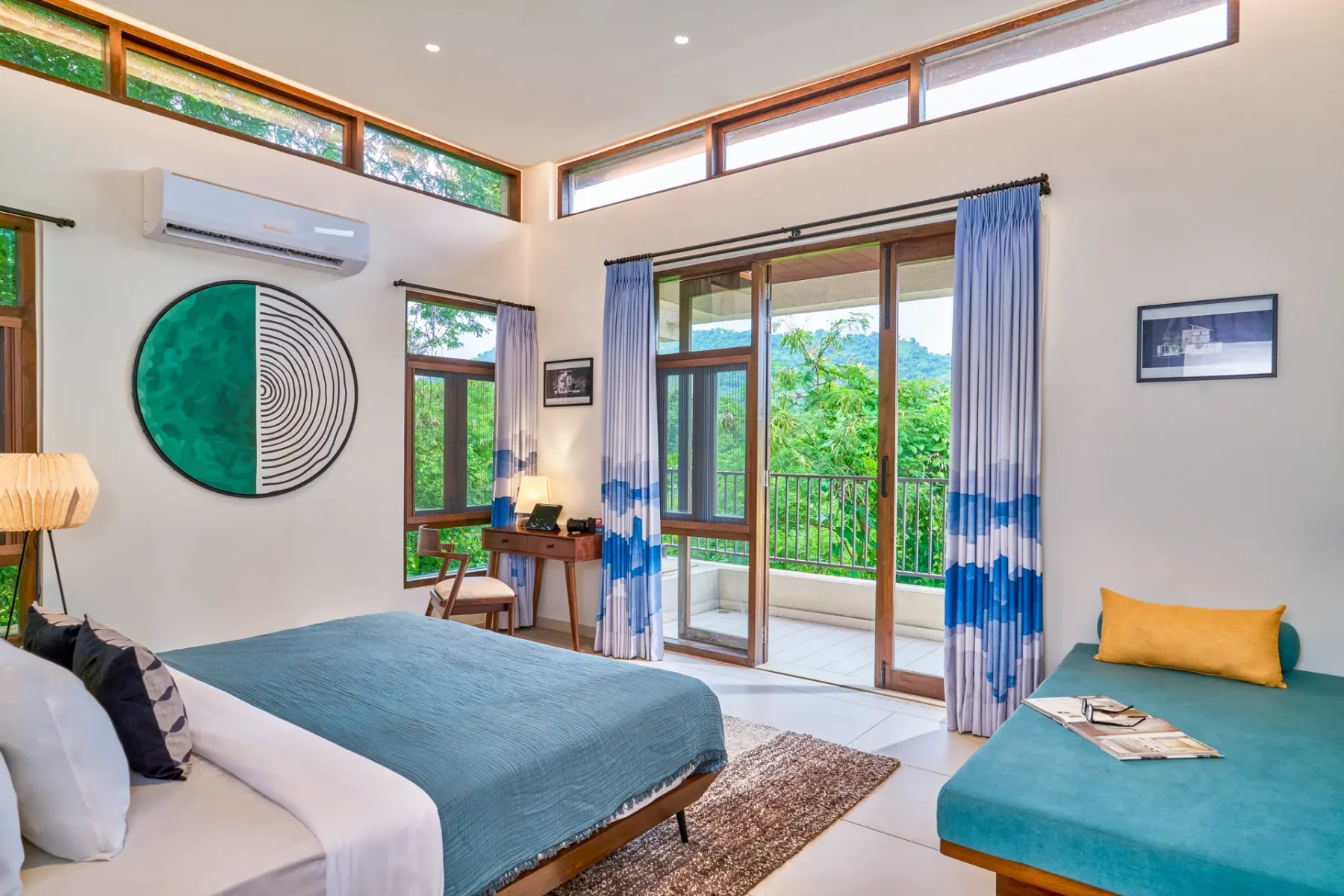 A bright bedroom with a bed, seating, and glass doors opening to a balcony.