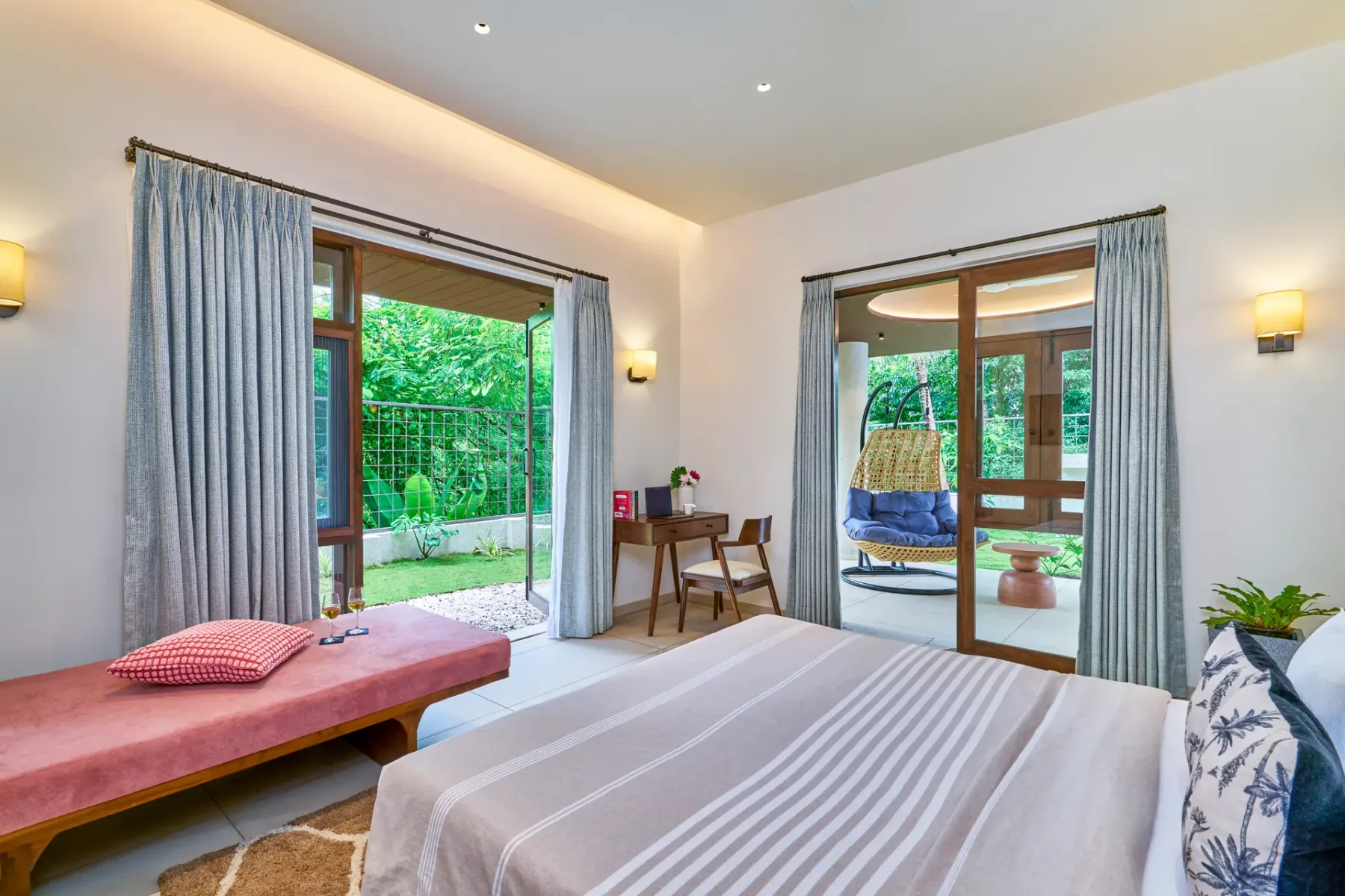 A bright bedroom opens onto a garden through large glass doors.