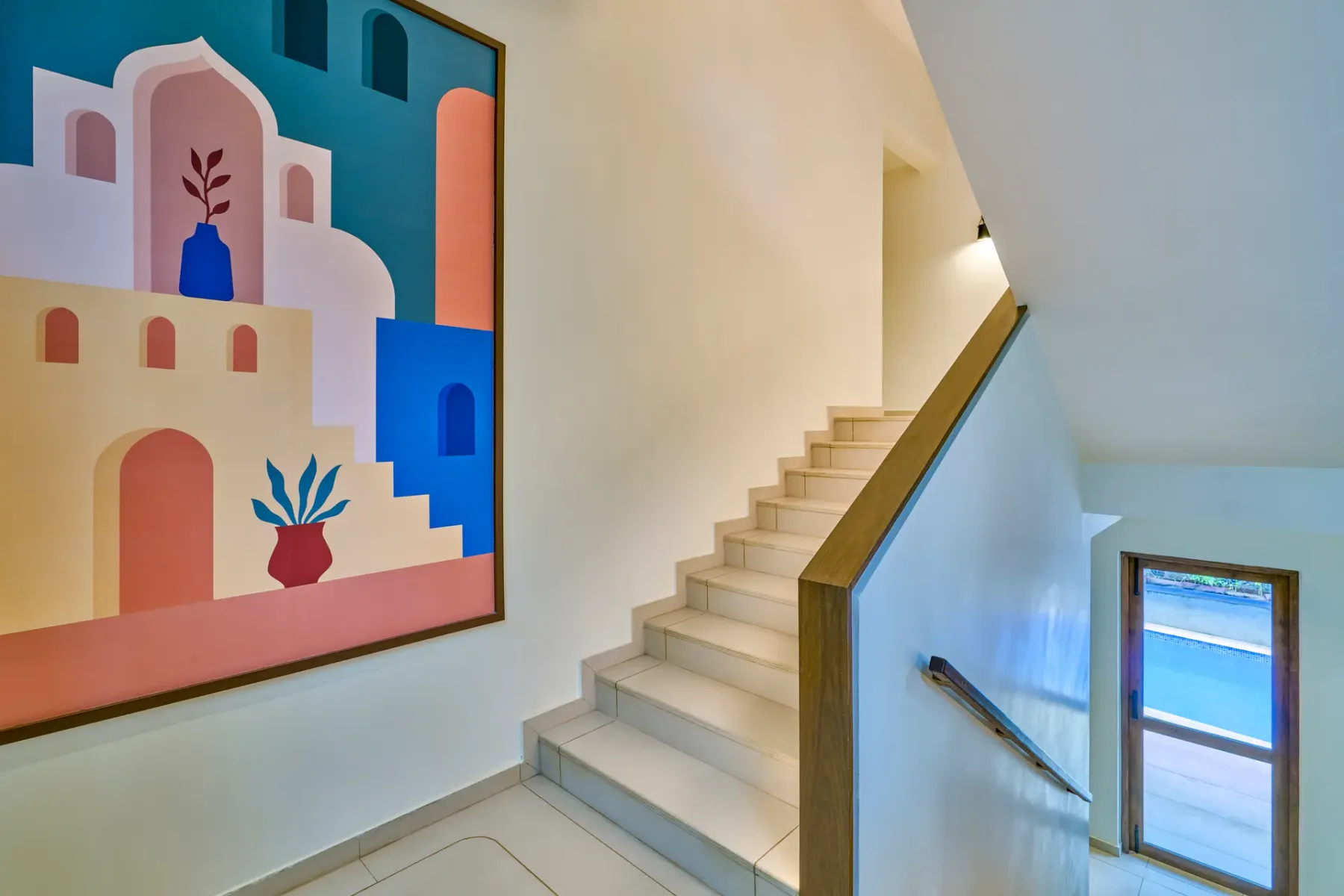 An indoor staircase beside a colorful geometric wall artwork.