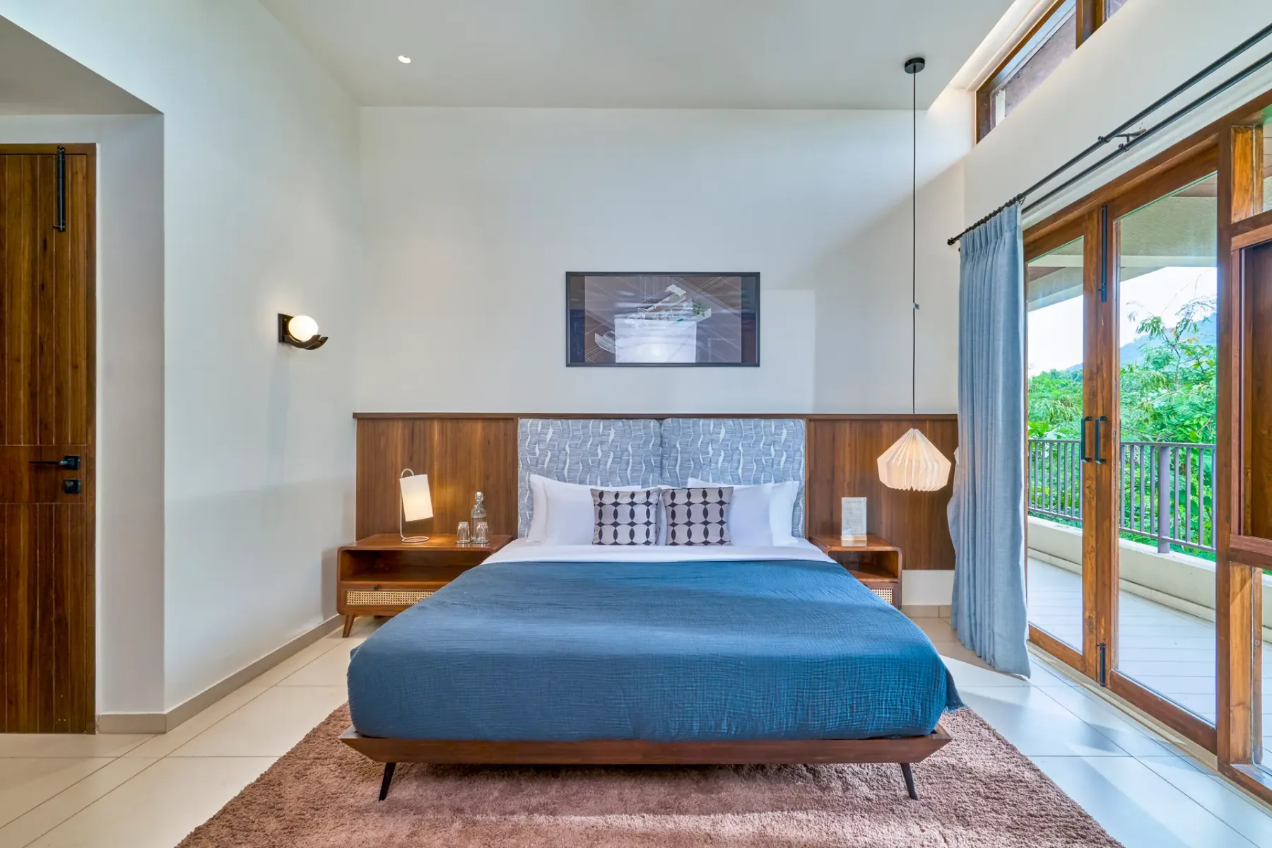 A bedroom with a bed, bedside tables, and glass doors opening onto a balcony.