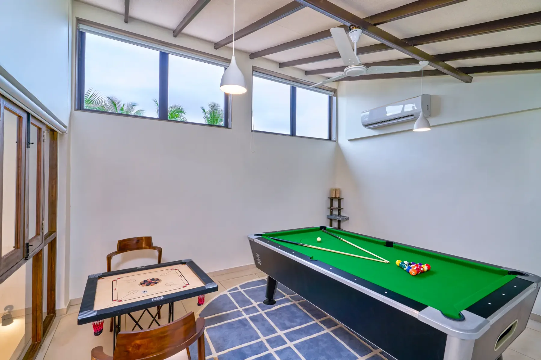 A recreation room with a green billiards table and a small game table.