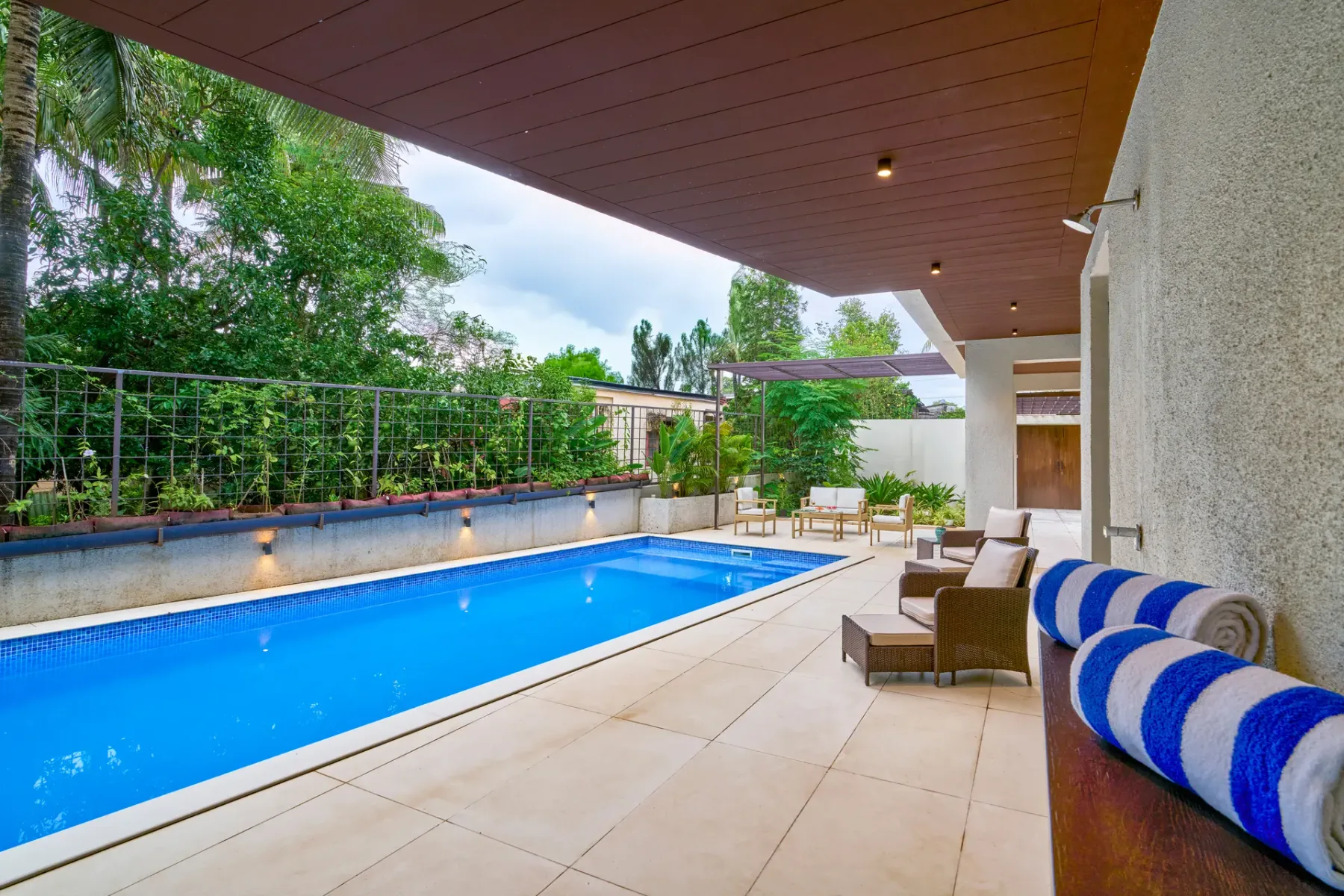 A swimming pool and tiled patio sit beside an outdoor seating area.