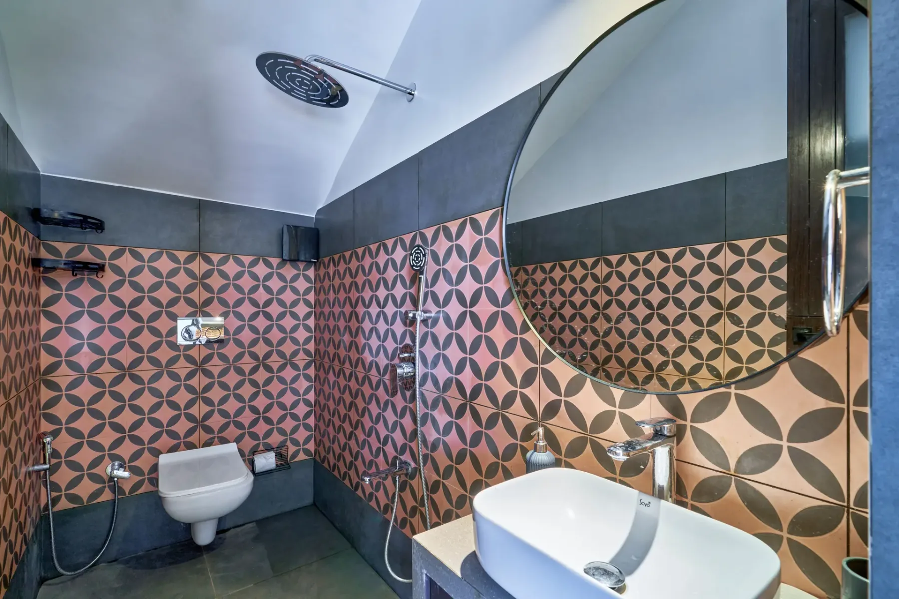 A tiled bathroom with a wall-mounted toilet and sink beneath a large mirror.