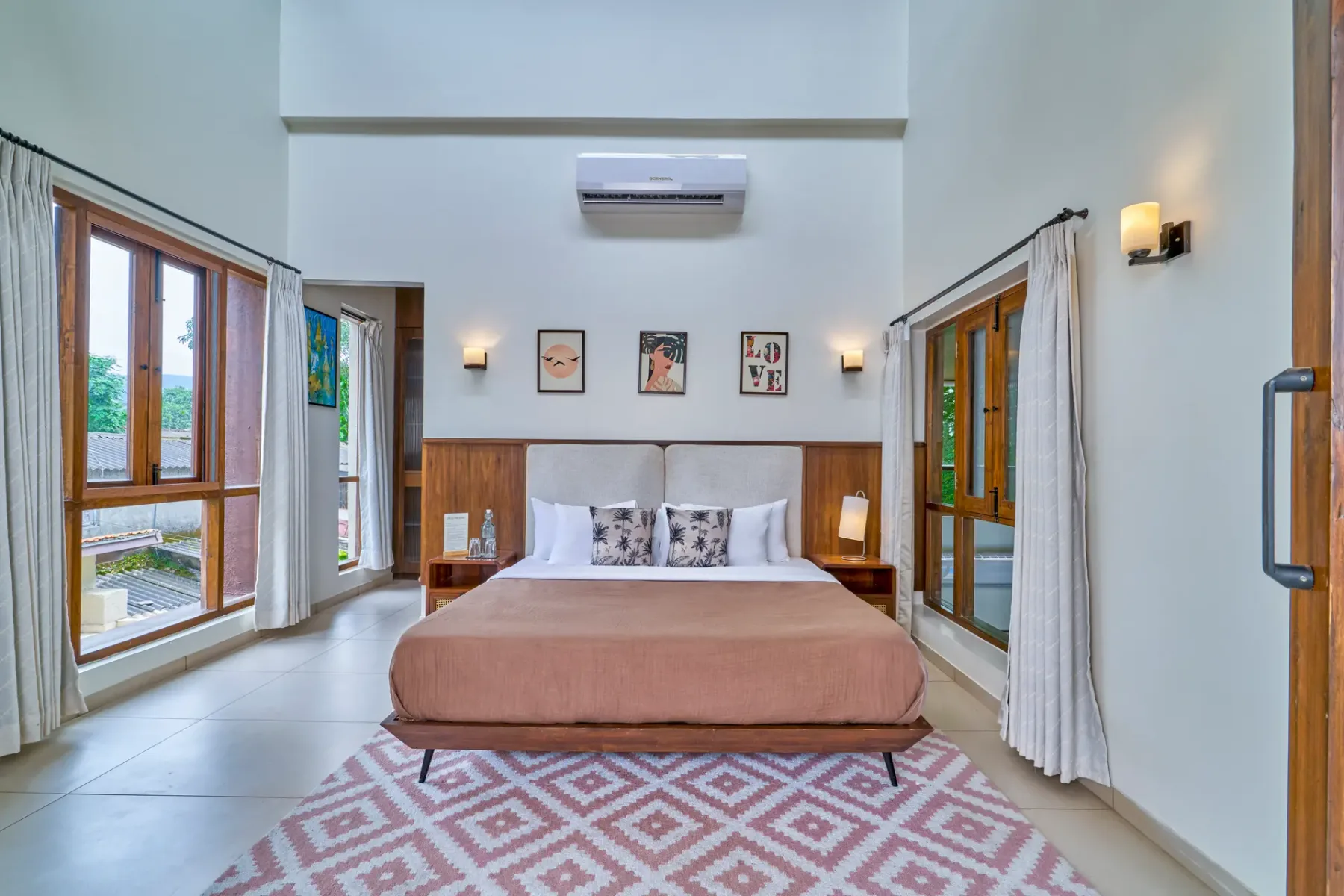 A bedroom with a bed, curtained windows, and a patterned rug.