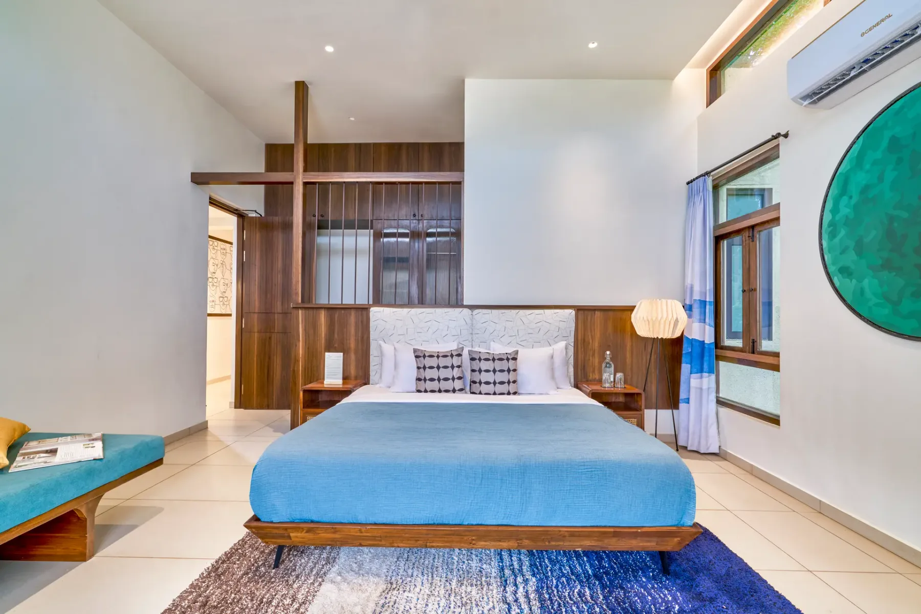 A bedroom with a blue-covered bed and wood-paneled wall.