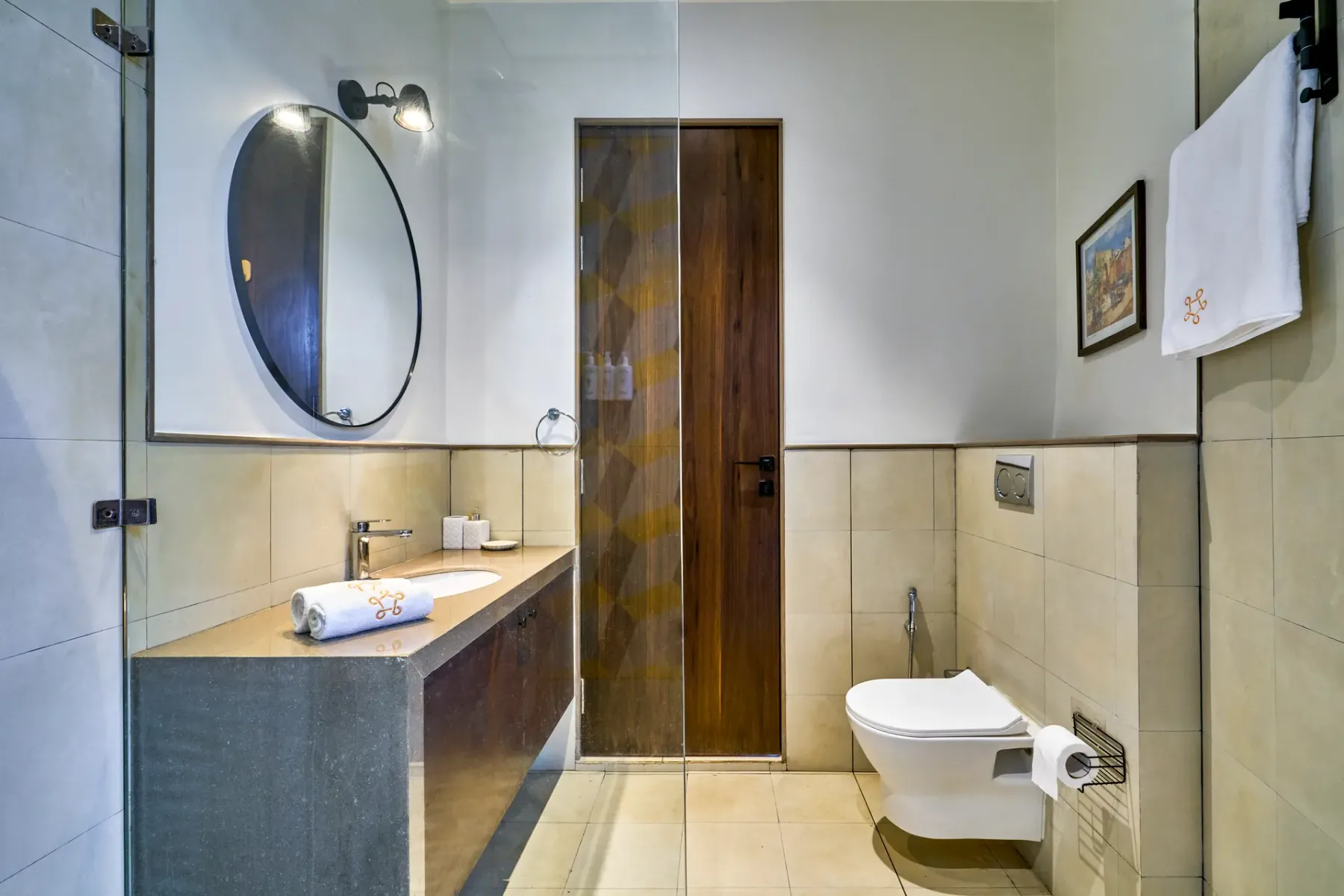 A bathroom with a sink, oval mirror, and toilet.