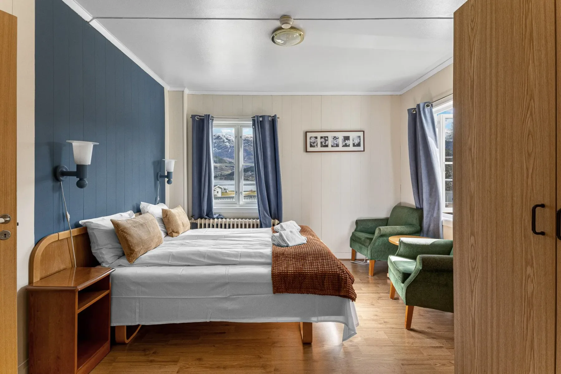 Bedroom with a bed, green chair, blue walls and a window.