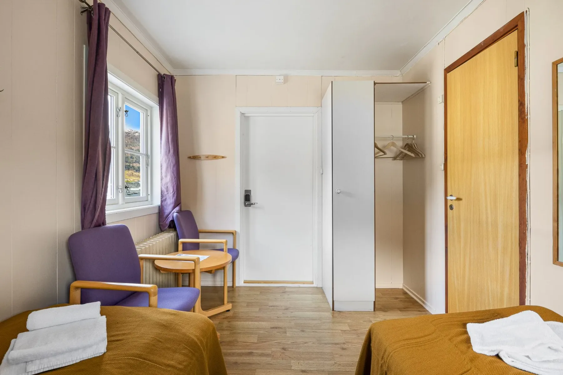 Bedroom with two beds, a purple chair and a wardrobe.