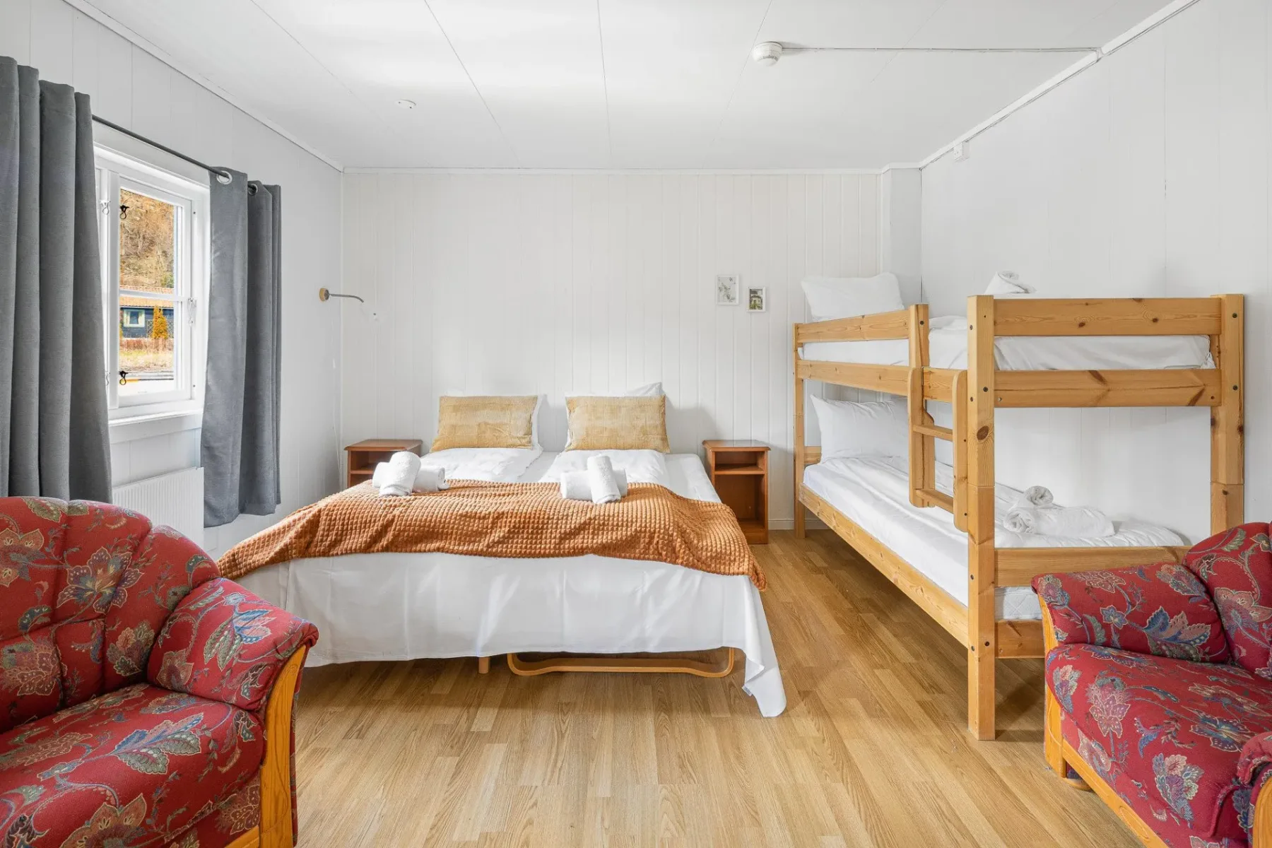 Bedroom with a double bed, bunk bed and red armchairs.