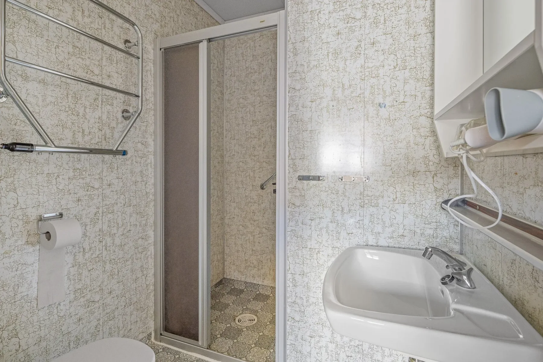 Tiled bathroom with a shower, sink and mirrored cabinet.
