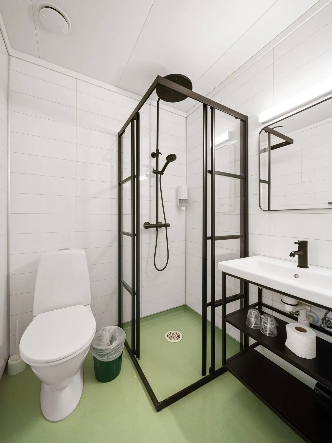 Compact bathroom with a toilet, glass shower and sink.