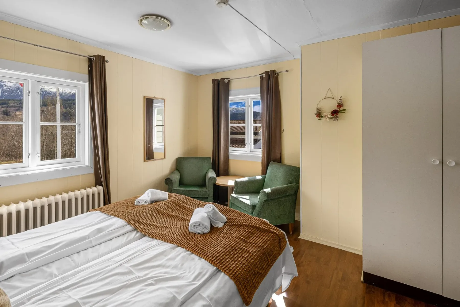 Twin bedroom with green chairs and a white wardrobe.