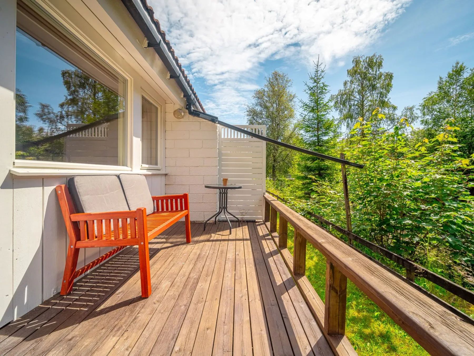 Wooden deck with orange chairs beside a house.