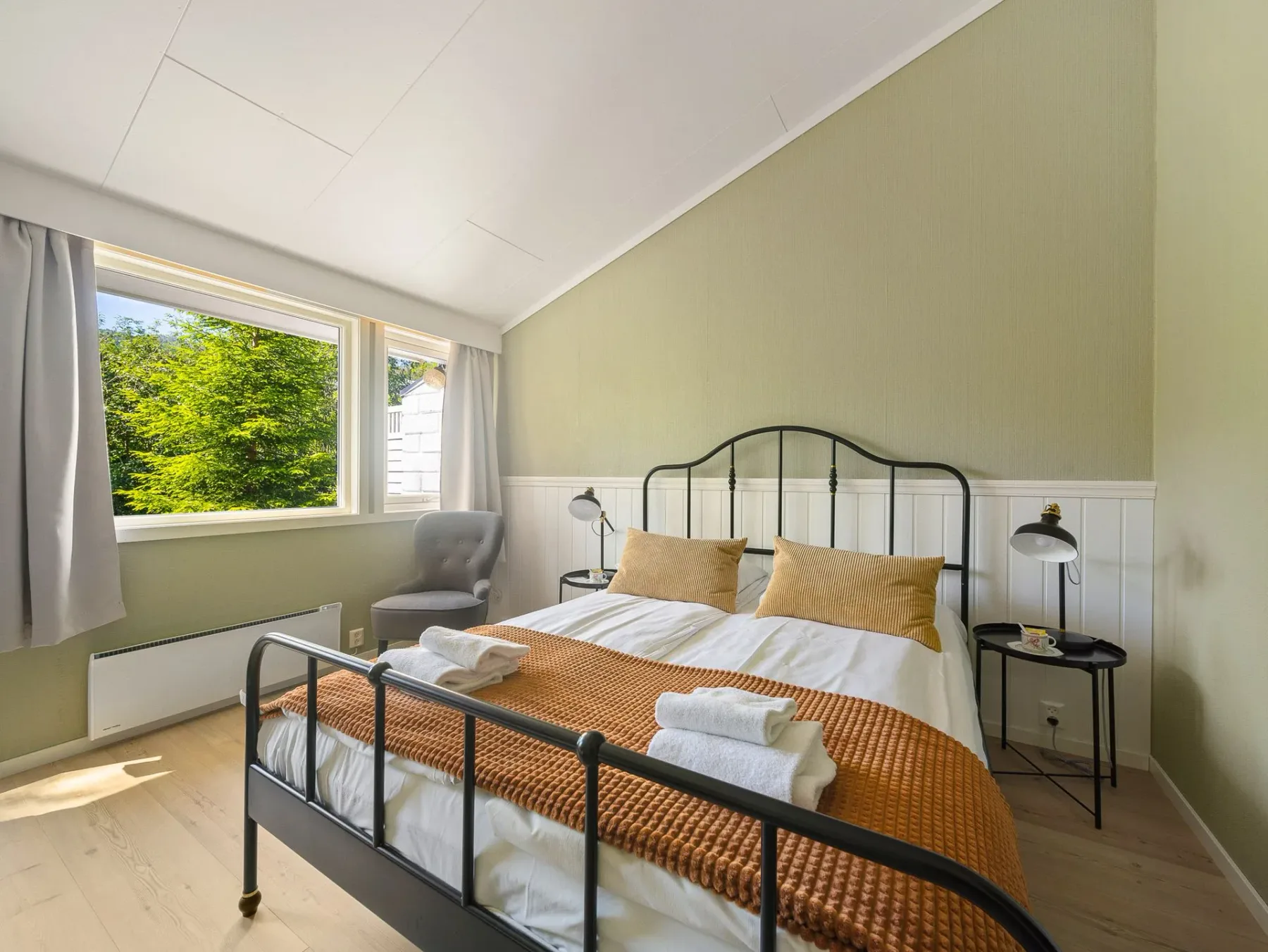 Bedroom with a black metal bed and a large window.