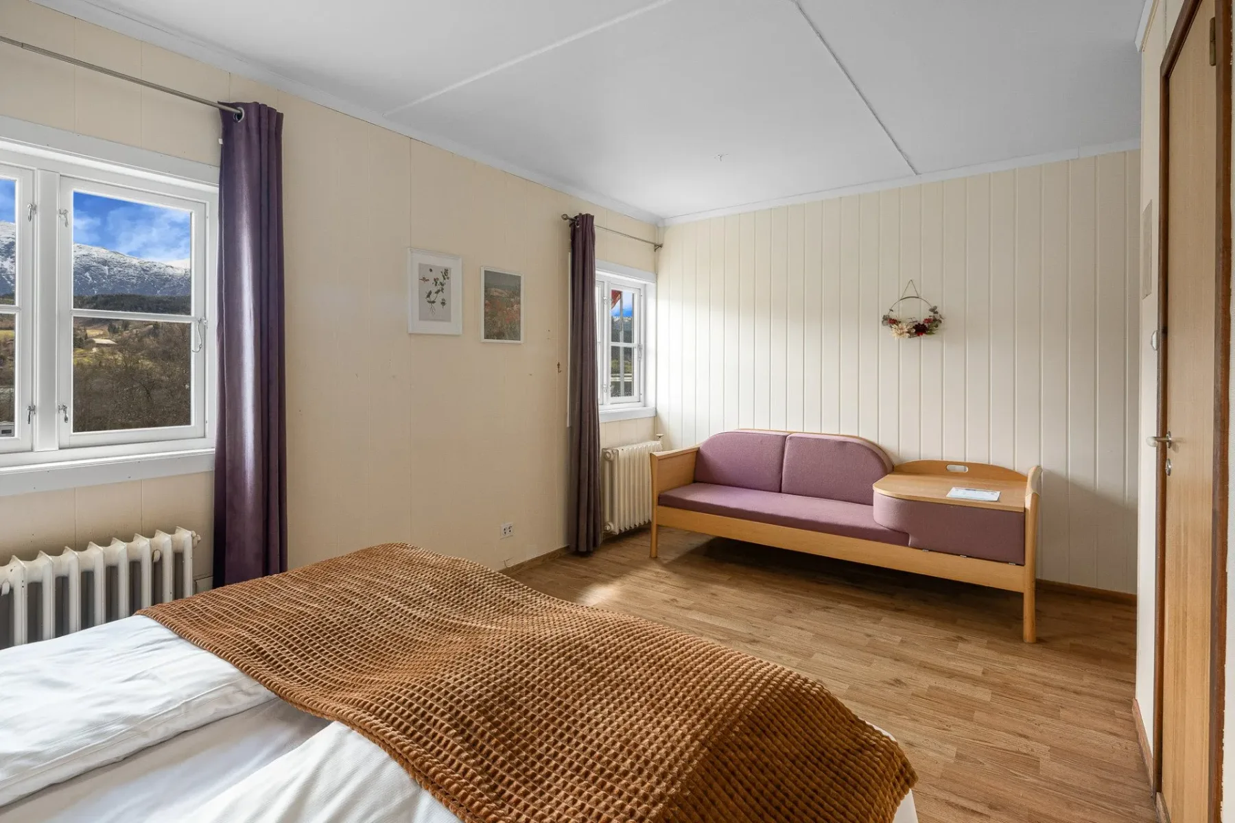 Bedroom with a bed, purple sofa and windows.