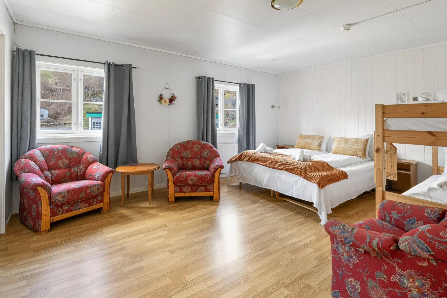 Bedroom with a bed, bunk bed and red armchairs.