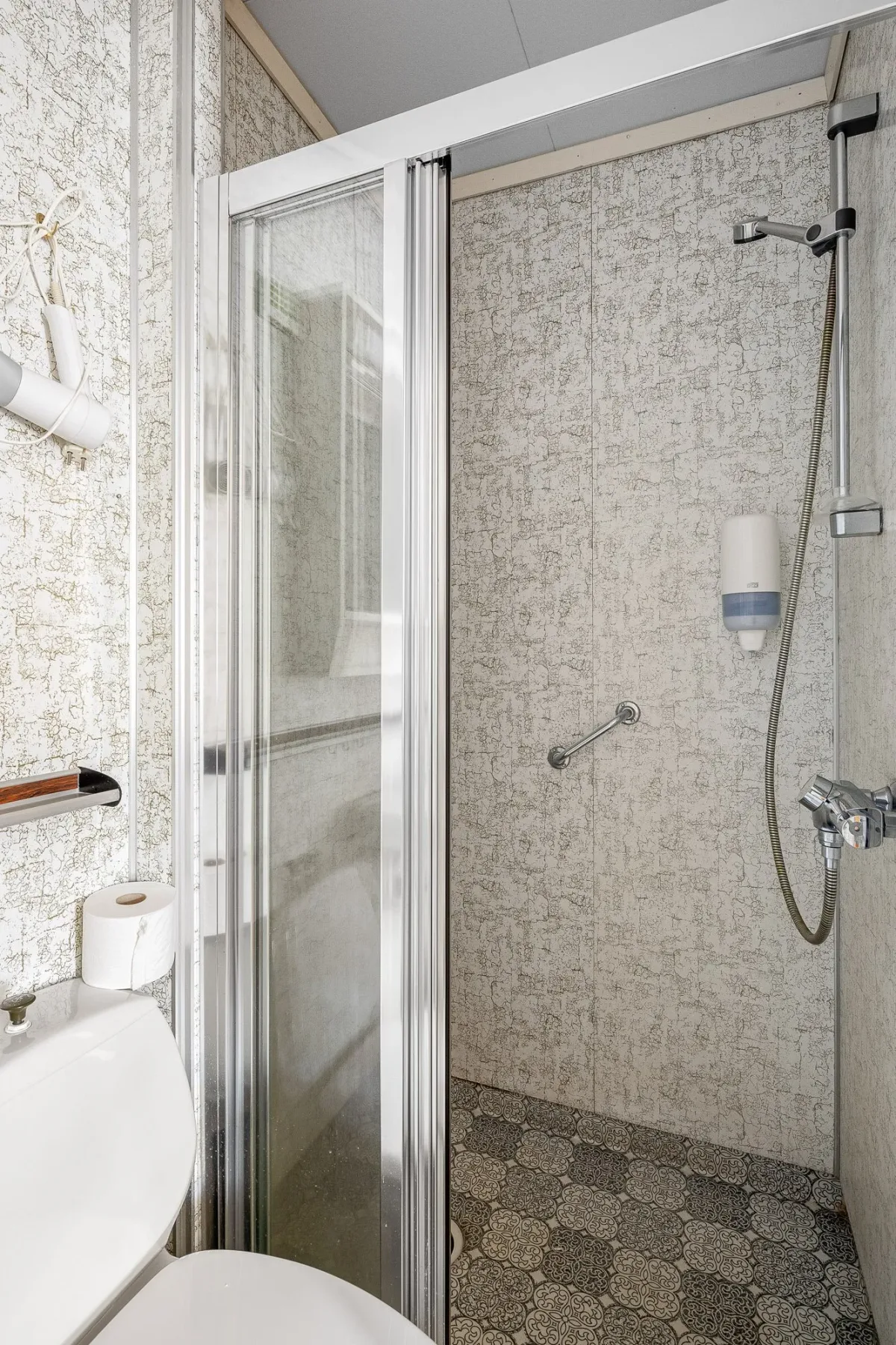 Tiled shower stall with a glass door.
