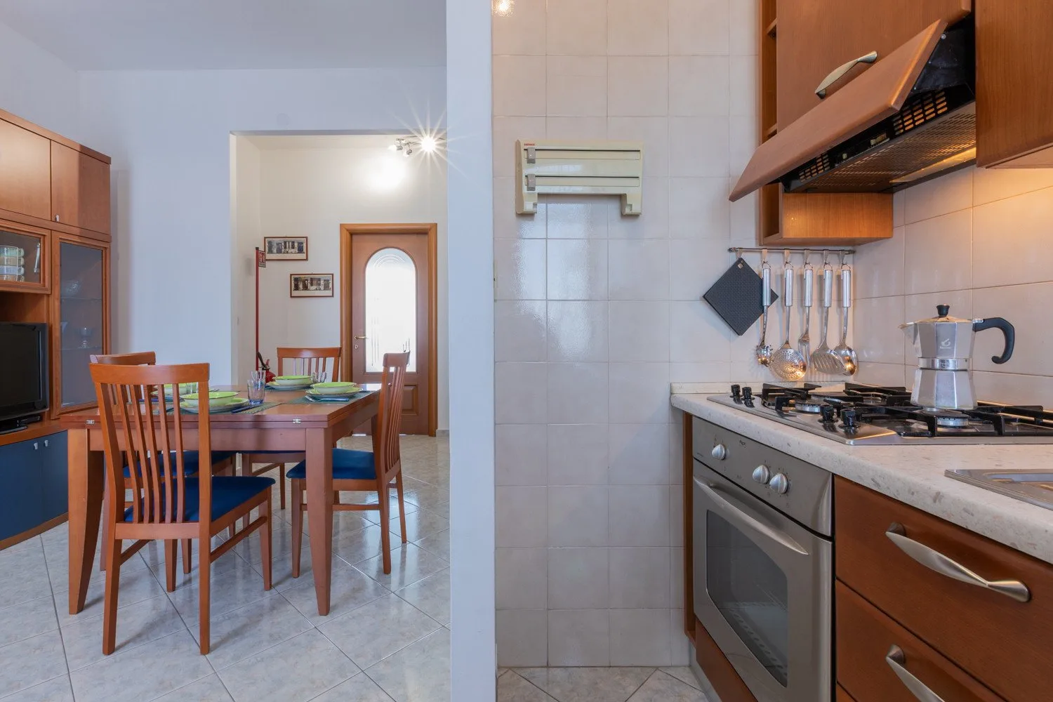 A kitchen with a dining area, wooden cabinets, and a table with chairs.