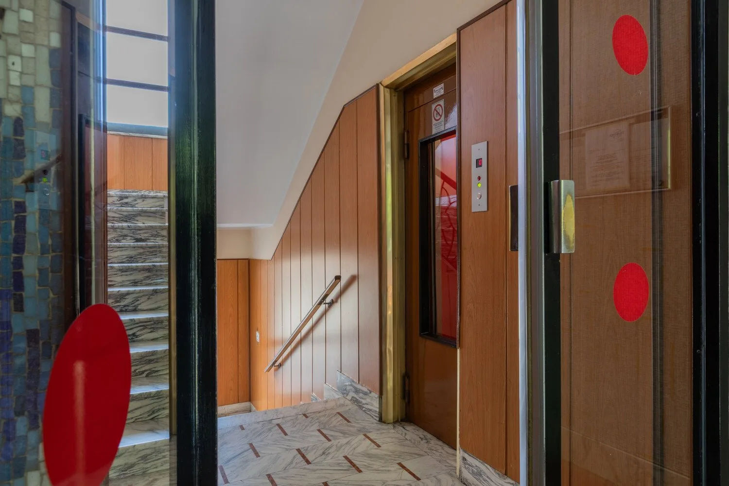 A stairwell landing with a handrail beside an elevator door.