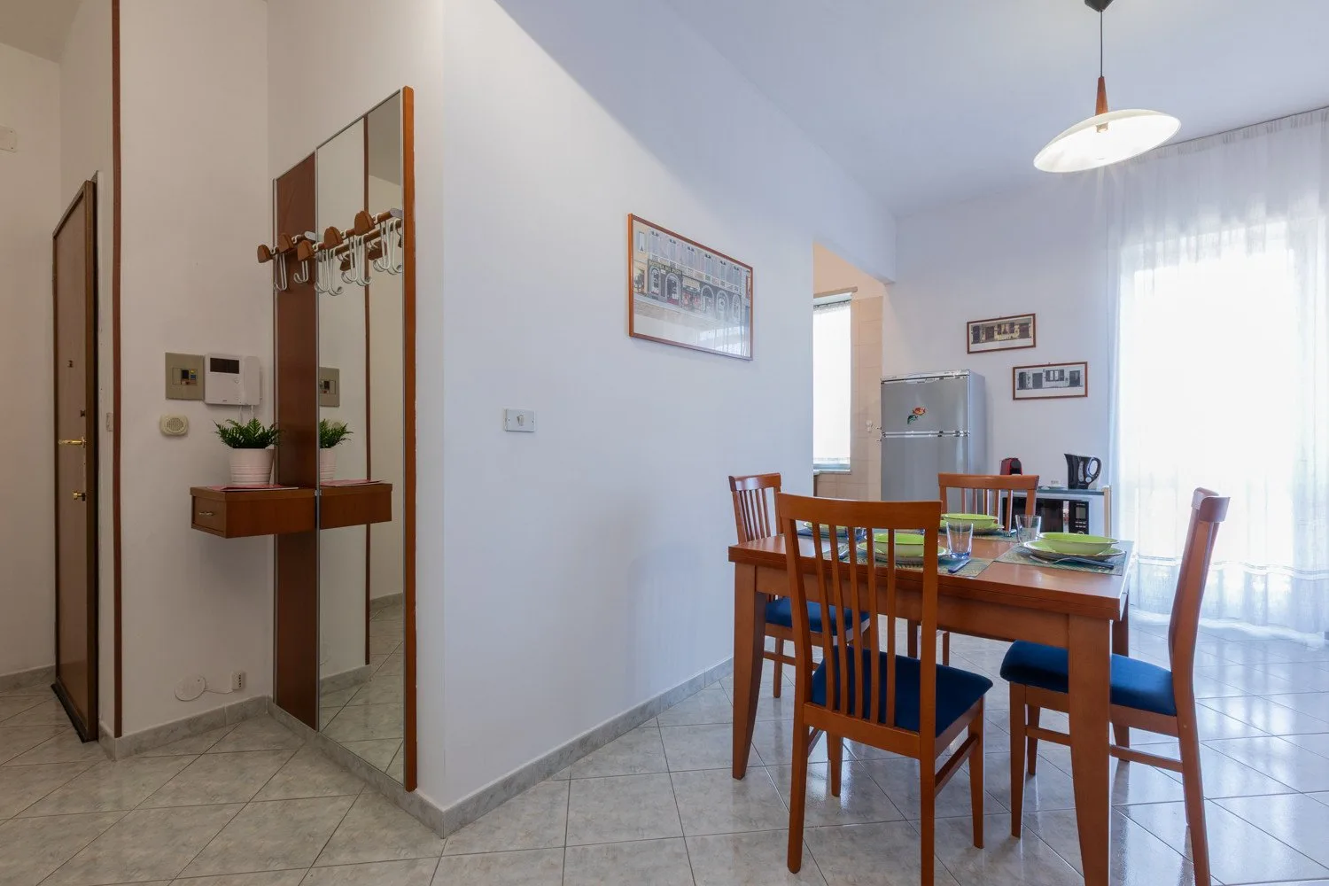 A dining area with a wooden table and chairs beside a bright window.
