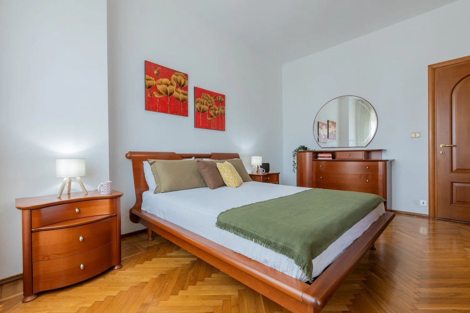 A bedroom with a wooden bed, dresser, and red wall art.