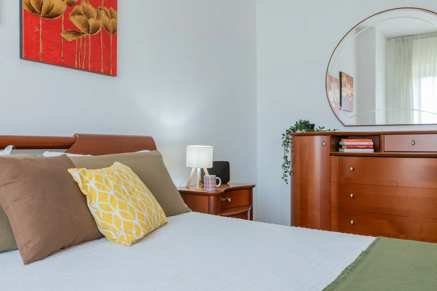 A bedroom with a bed, bedside table, and wooden dresser.