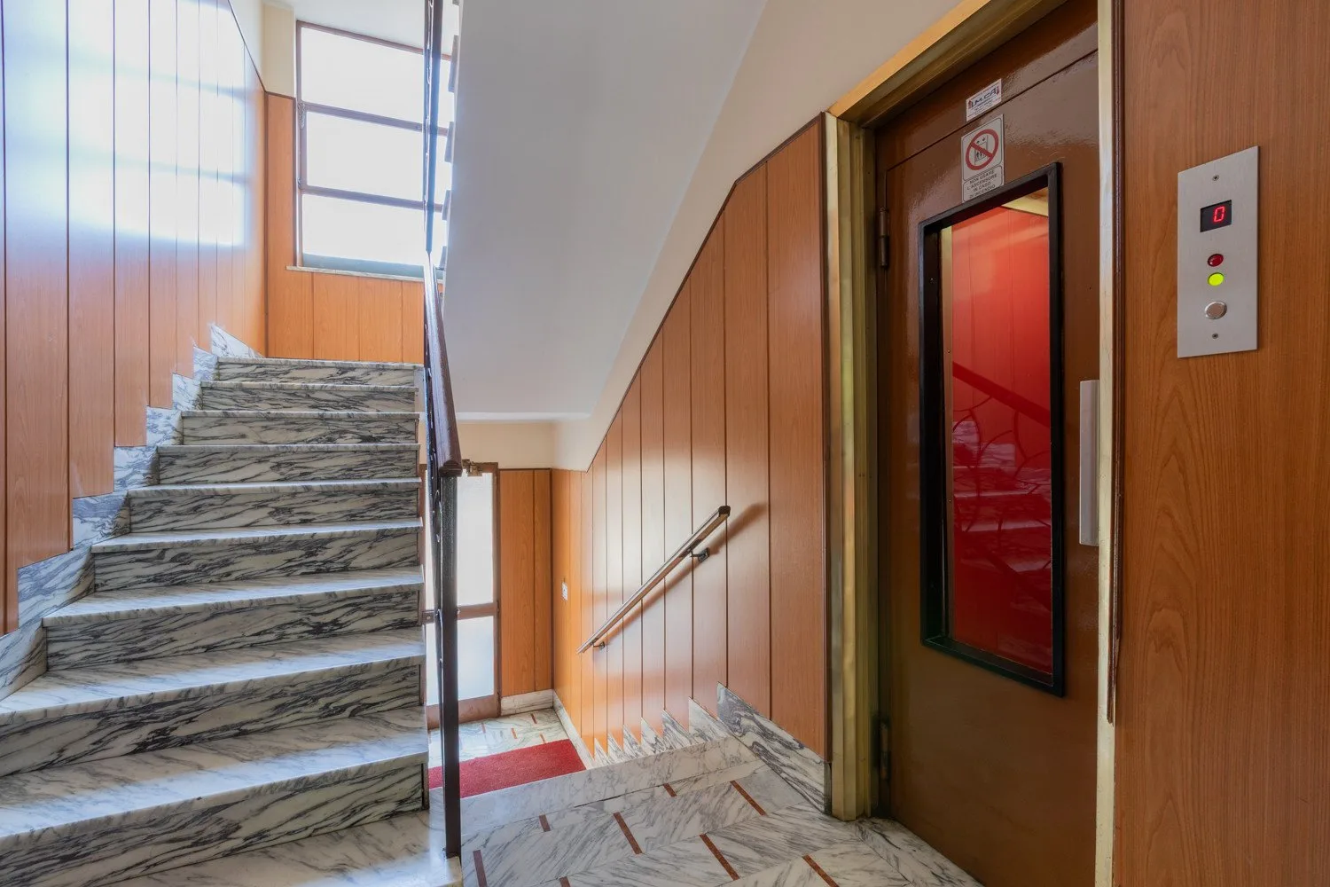 A stairwell with marble steps and an elevator.