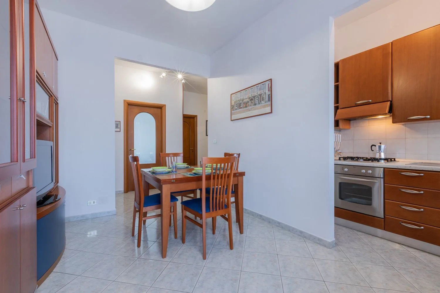 A dining area with a wooden table and chairs beside an open kitchen.