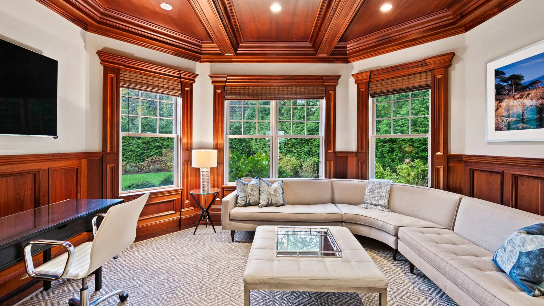Una sala de estar con asientos curvos, grandes ventanas y techo de madera.