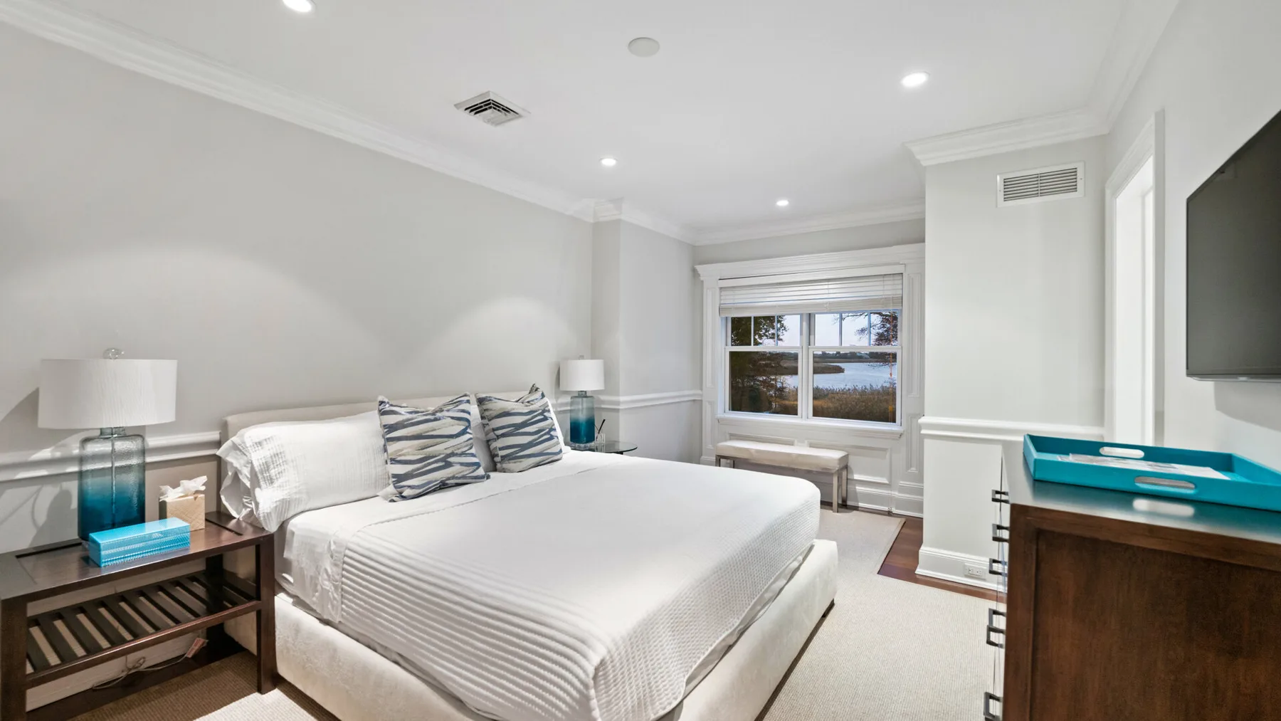 Un dormitorio luminoso con una cama bien hecha y una ventana.