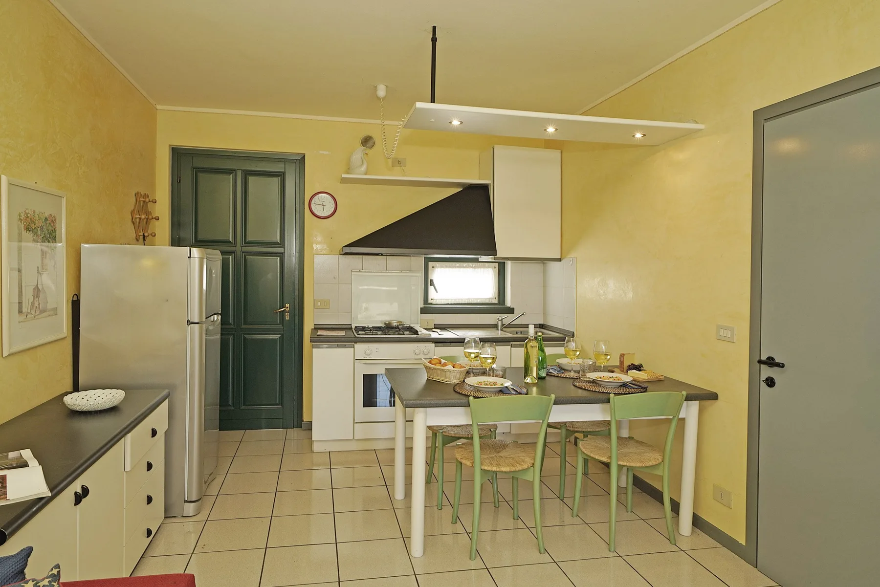 Una cocina con una mesa de comedor y sillas verdes.