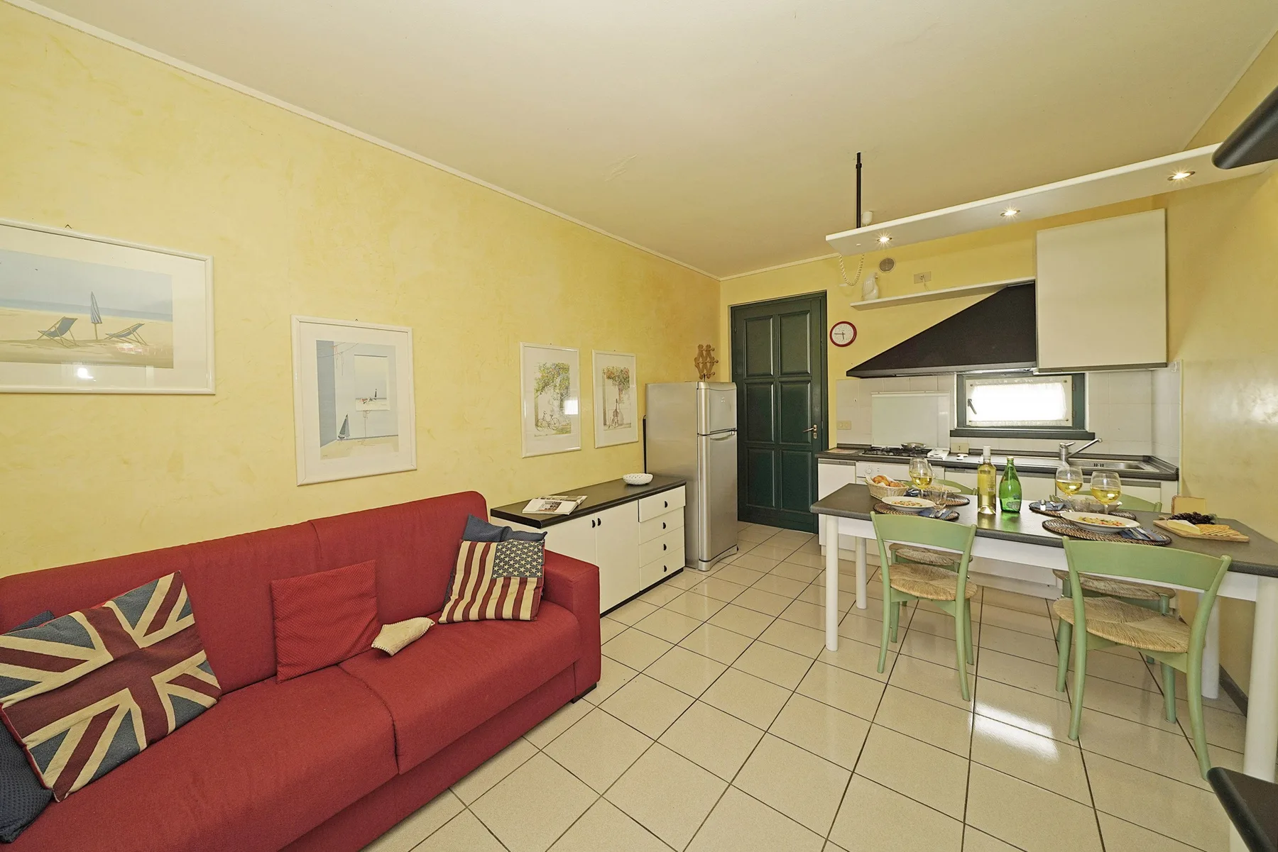 Sala y cocina integradas con asientos rojos y una mesa de comedor.