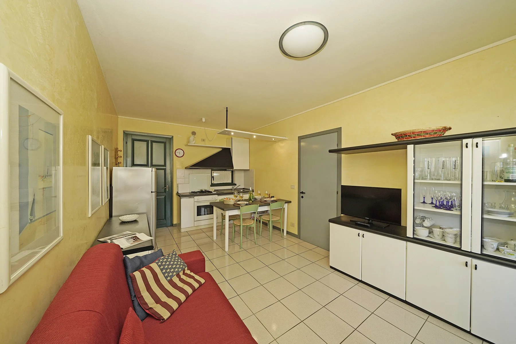 Sala de estar y cocina pequeña con un sofá rojo y una mesa de comedor.