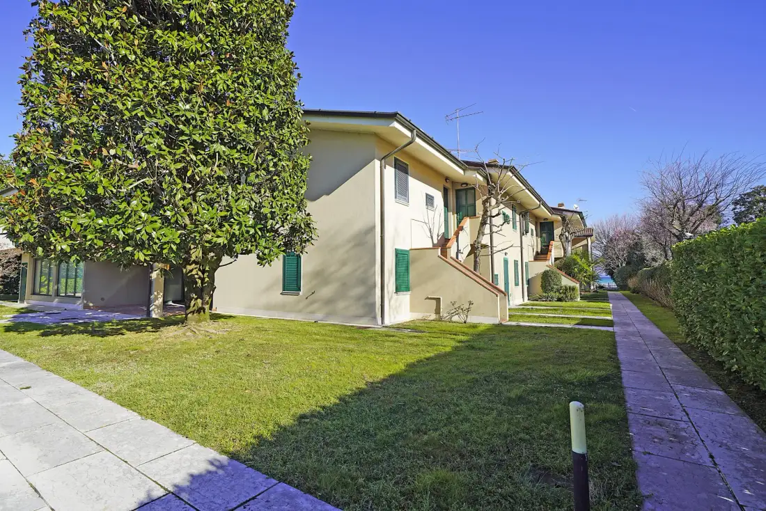 Una hilera de edificios residenciales bajos está junto a un césped y un camino pavimentado.