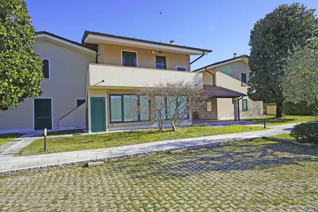 Un edificio residencial de varias plantas se encuentra junto a un sendero pavimentado y un césped ajardinado.