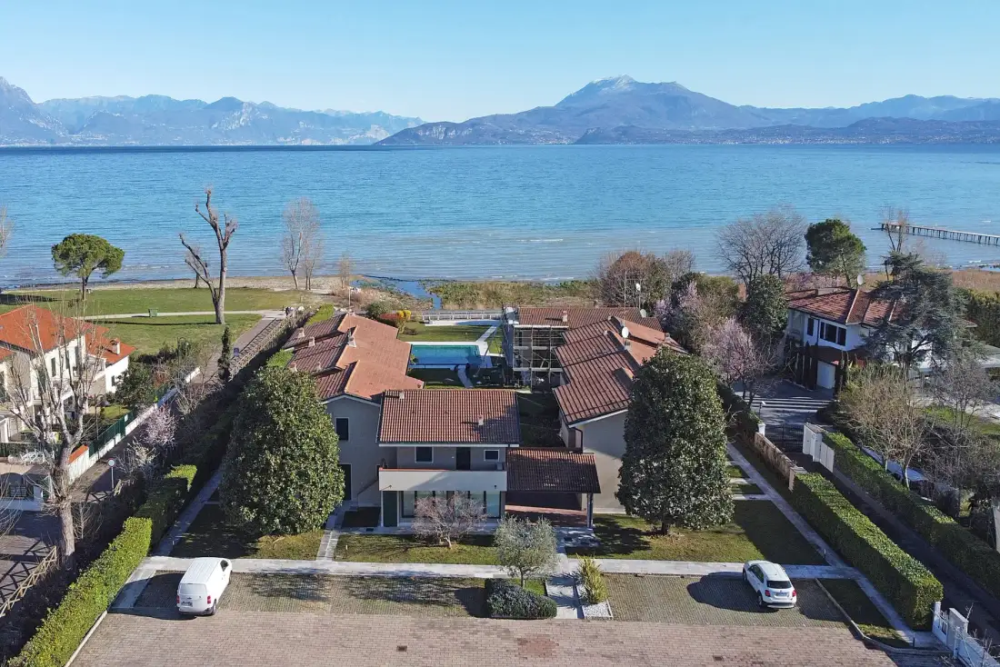 Vista aérea de casas junto al lago, con el lago y las montañas al fondo.