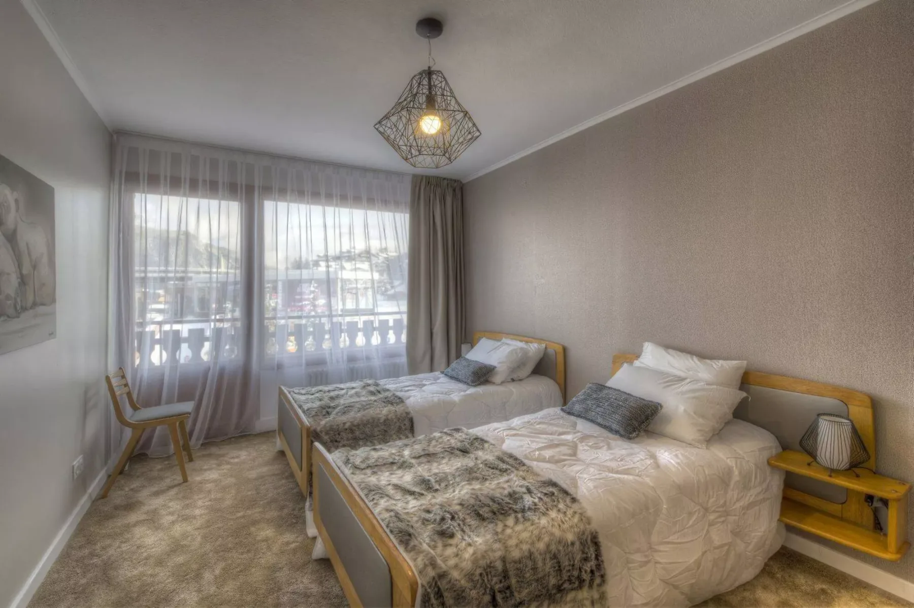 A bedroom with two beds, a window, and sheer curtains.