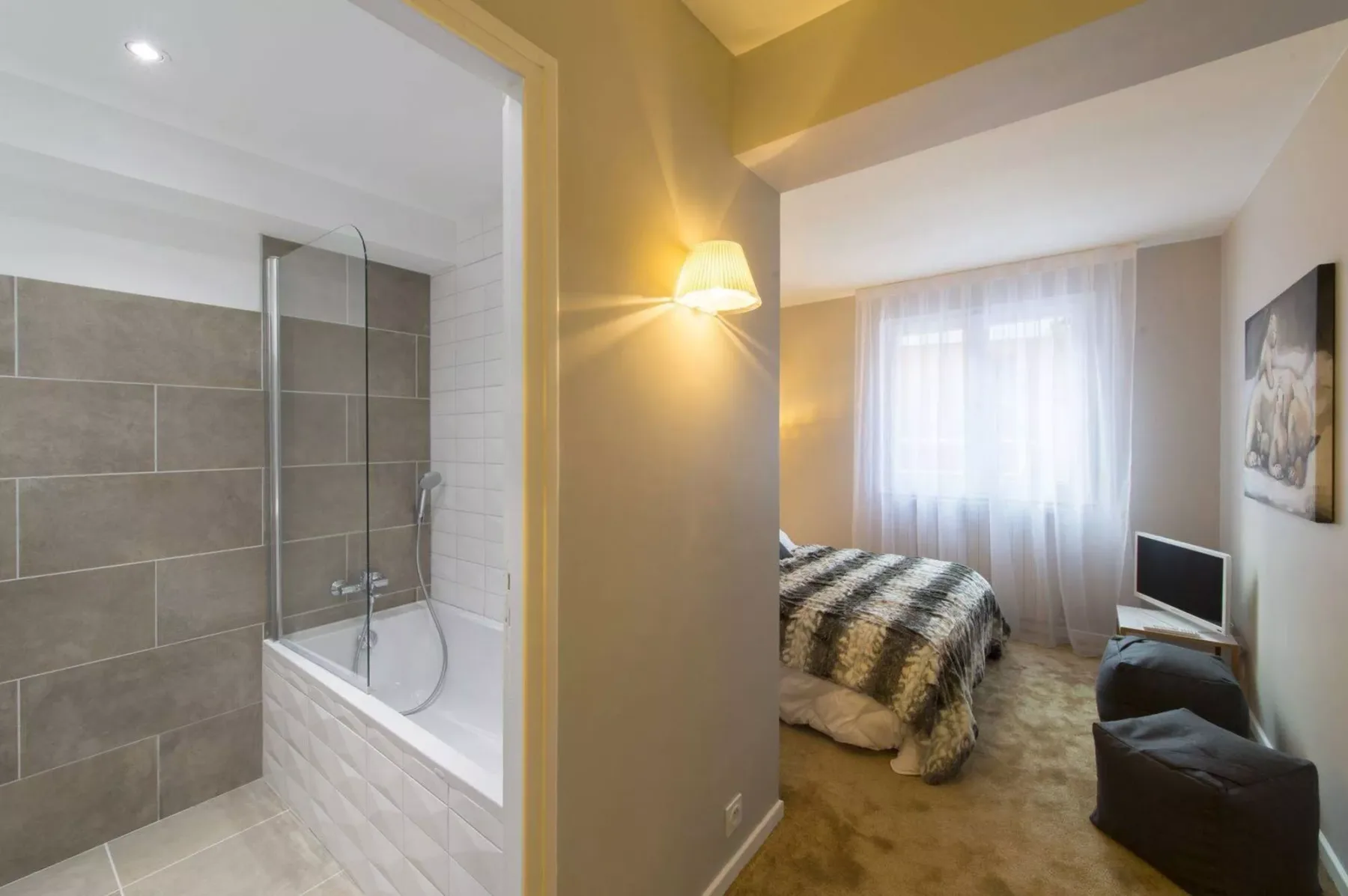A bedroom with a bed, a small television, and an adjoining bathroom.