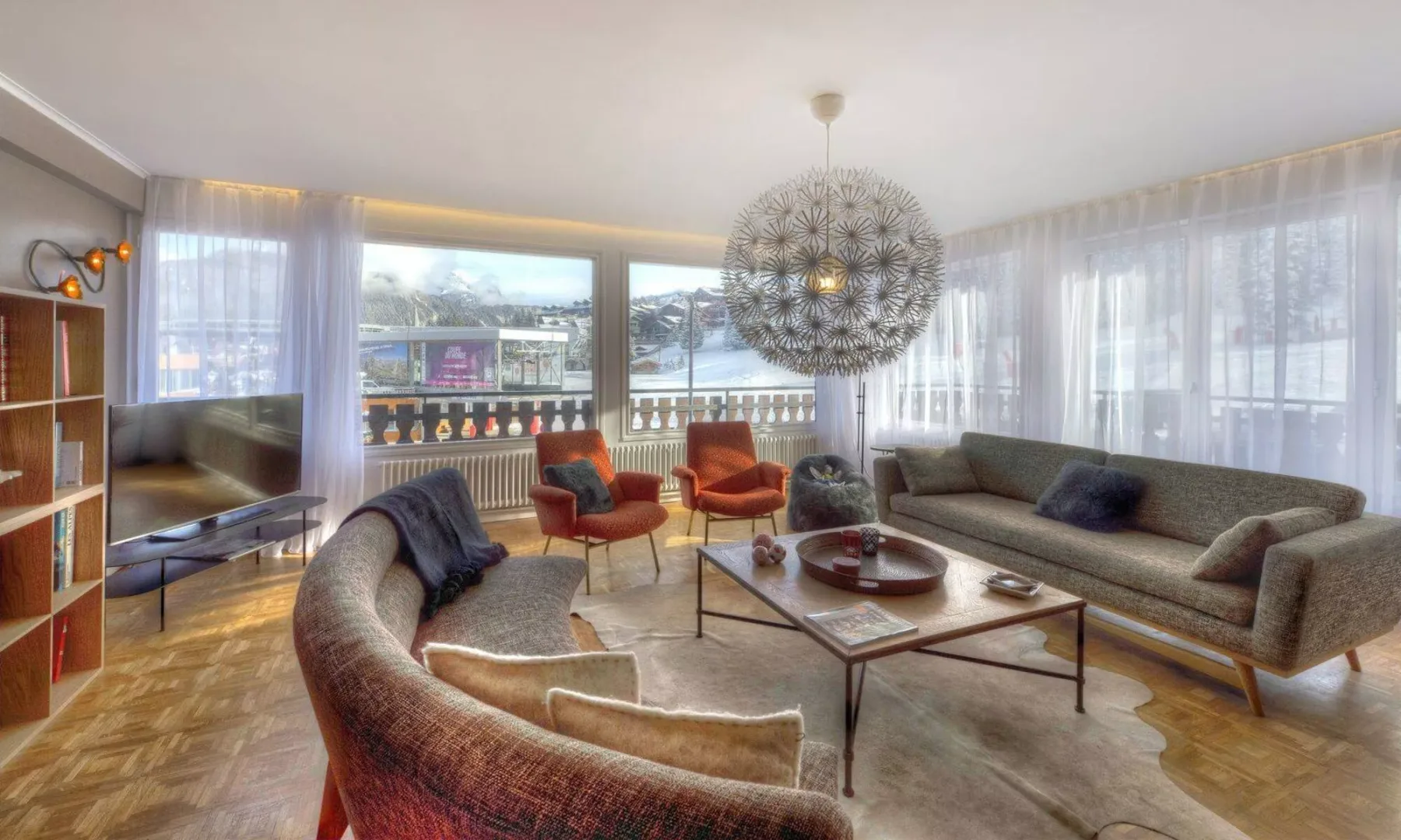 A bright living room has seating arranged around a coffee table beside large windows.