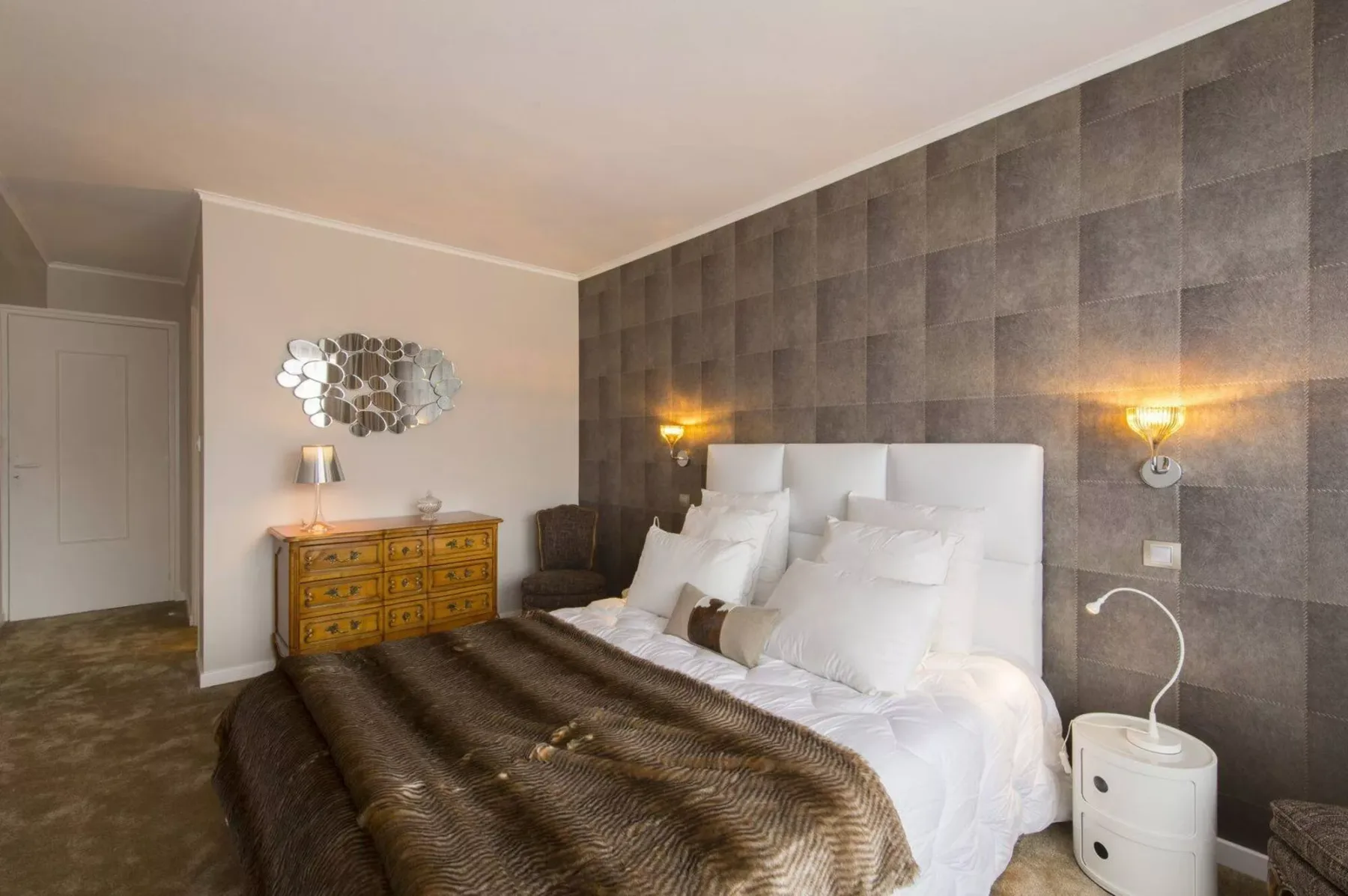 A bedroom with a large bed and a dark tiled accent wall.