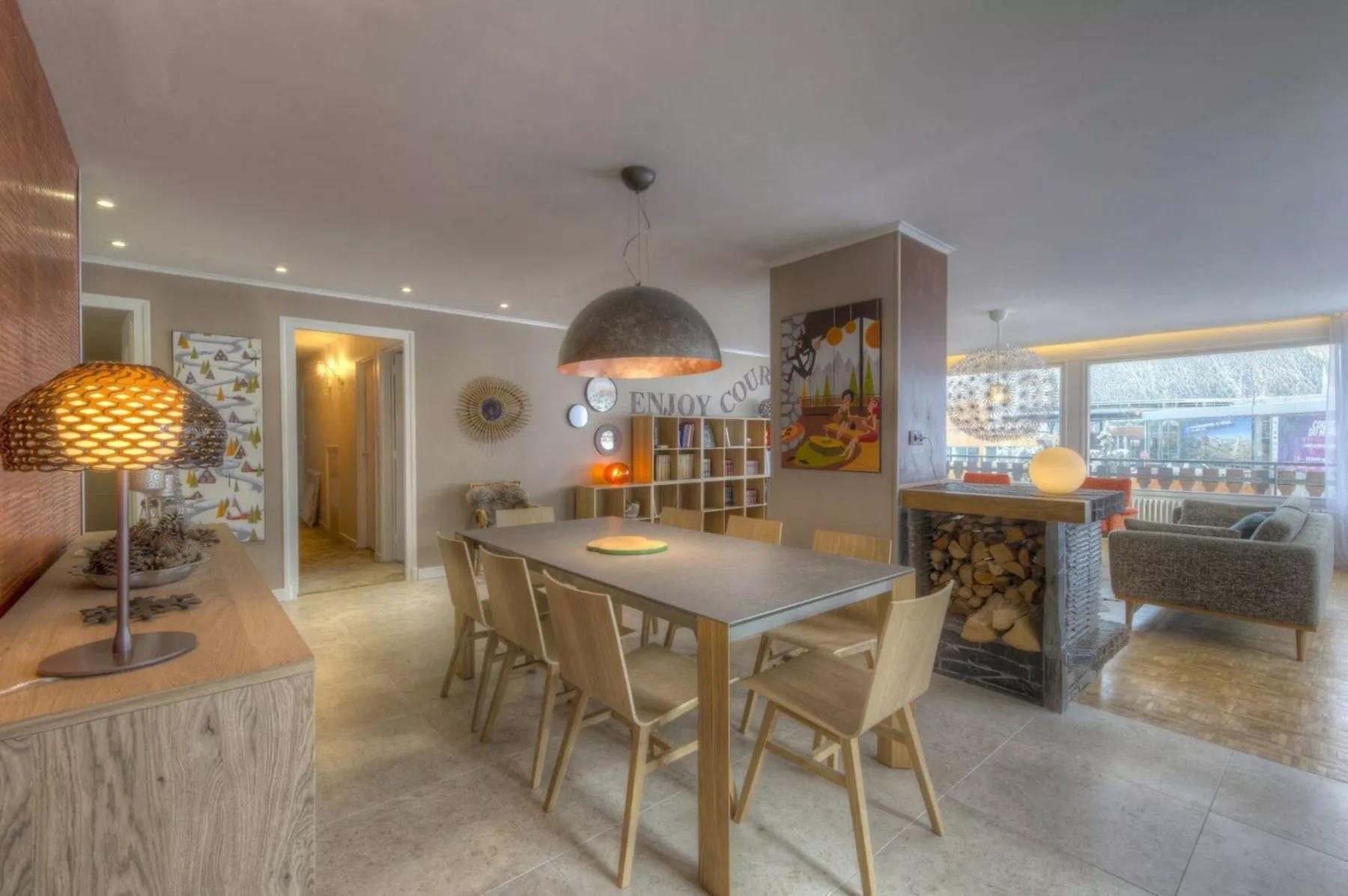 A dining area with a long table and seating beside an open living space.
