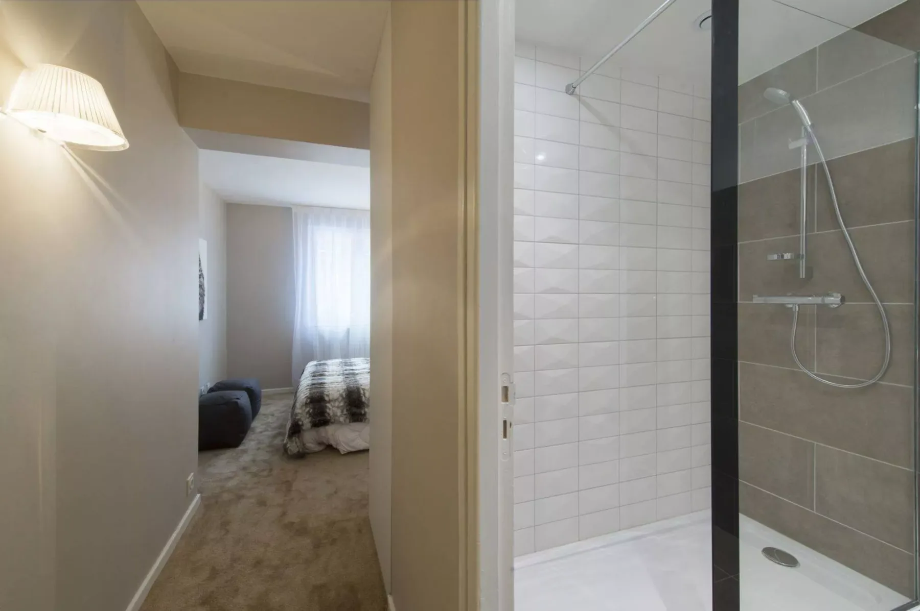 A hallway opens onto a bedroom beside a tiled shower.