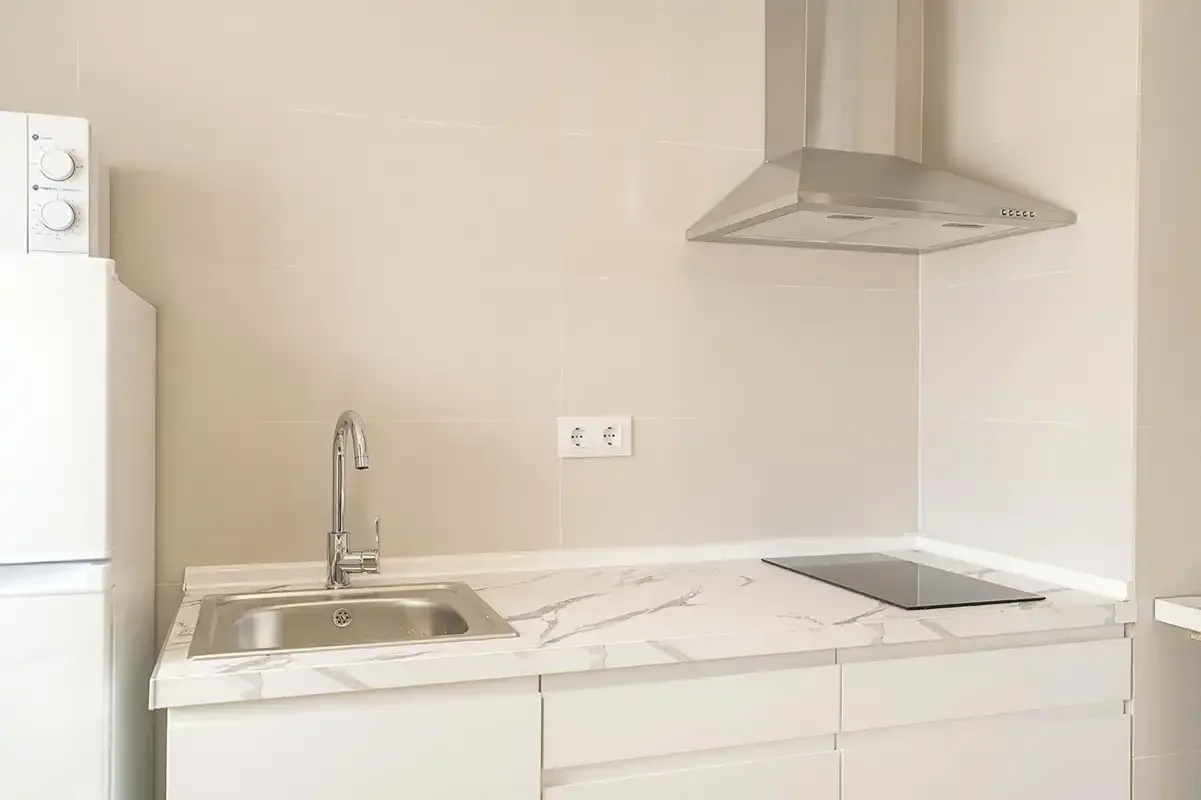 Una cocina luminosa con fregadero, placa de cocina y campana extractora.