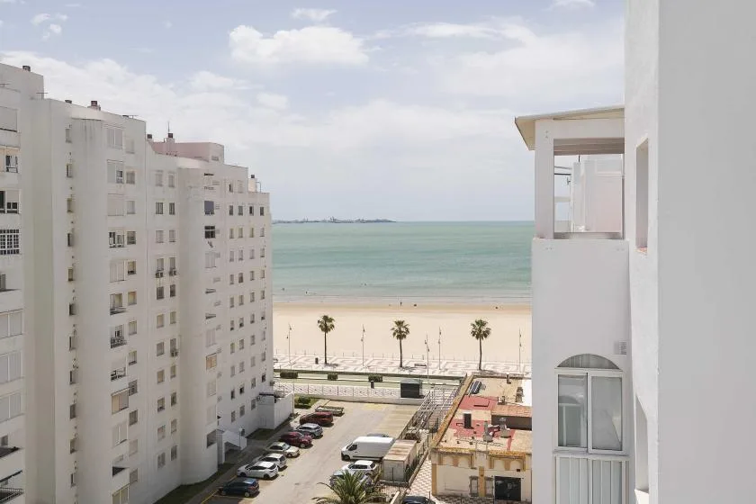 Vista de la playa y el océano entre edificios blancos.