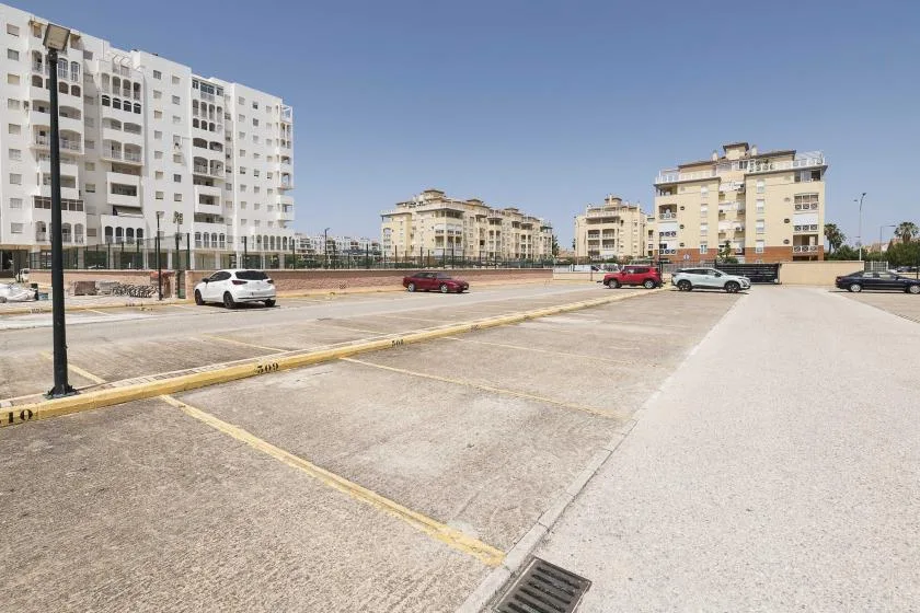 Una zona de estacionamiento al aire libre con edificios de apartamentos al fondo.